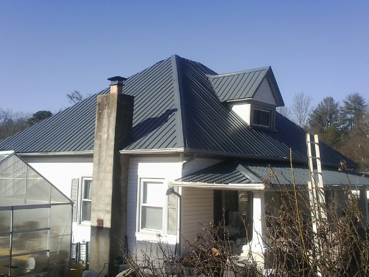 Dark blue standing seam metal roof on a white farmhouse with dormer — Slate & Tile Roof Repair by Roofing Brothers in Palmer