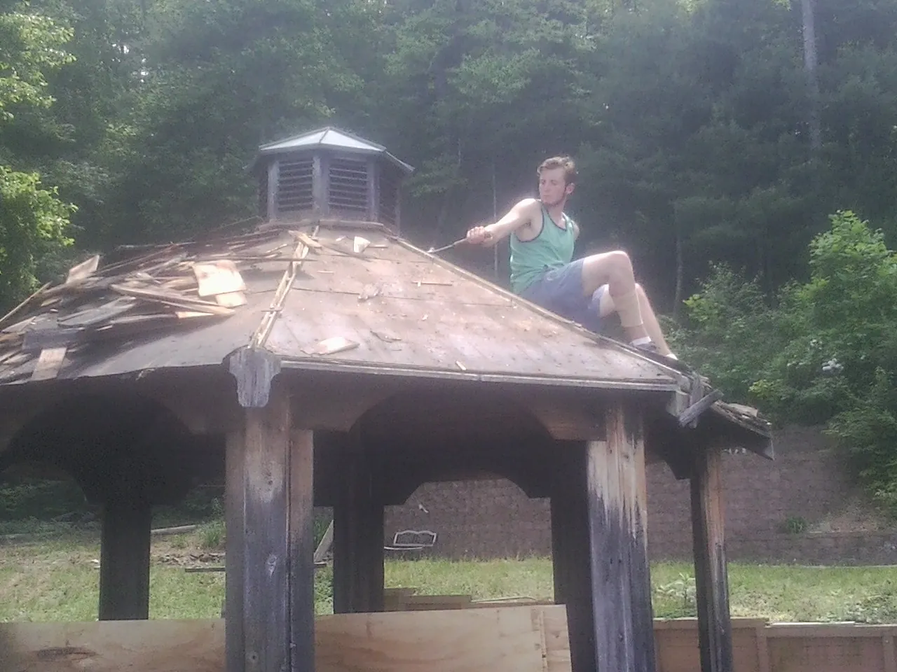 Tearing the old roof off a wooden gazebo before new shakes in Palmer