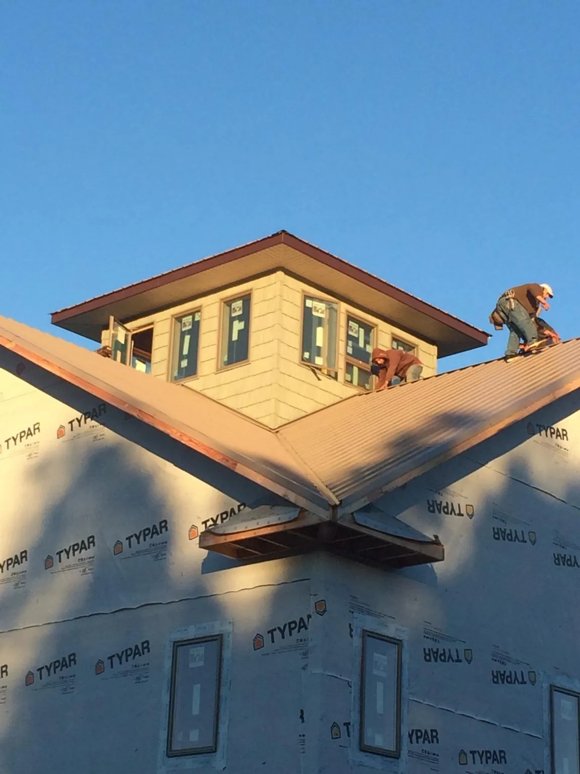 Roofers working around a rooftop cupola on a new metal roof at sunset — Roof Waterproofing in Palmer by Roofing Brothers